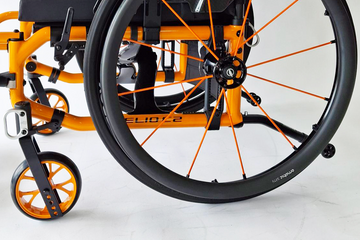 Close-up of an orange and black wheelchair with visible branding on a white background