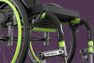 Close-up of a green and black Apex wheelchair on a purple background
